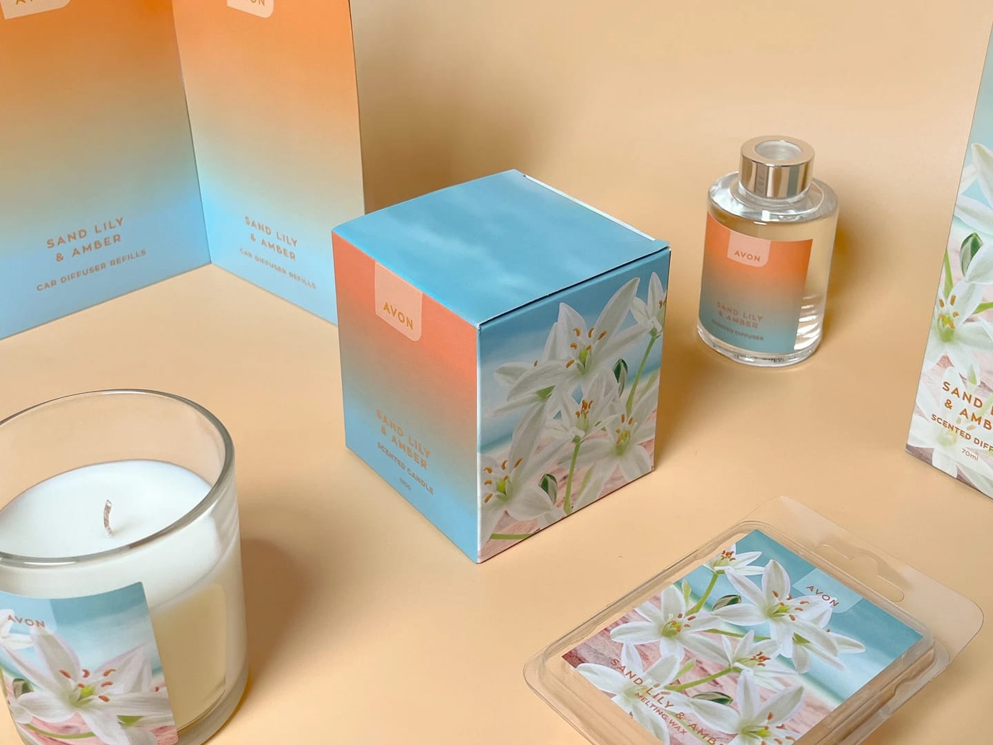 A stylish display featuring Avon products, including a candle, fragrance, and a gift box