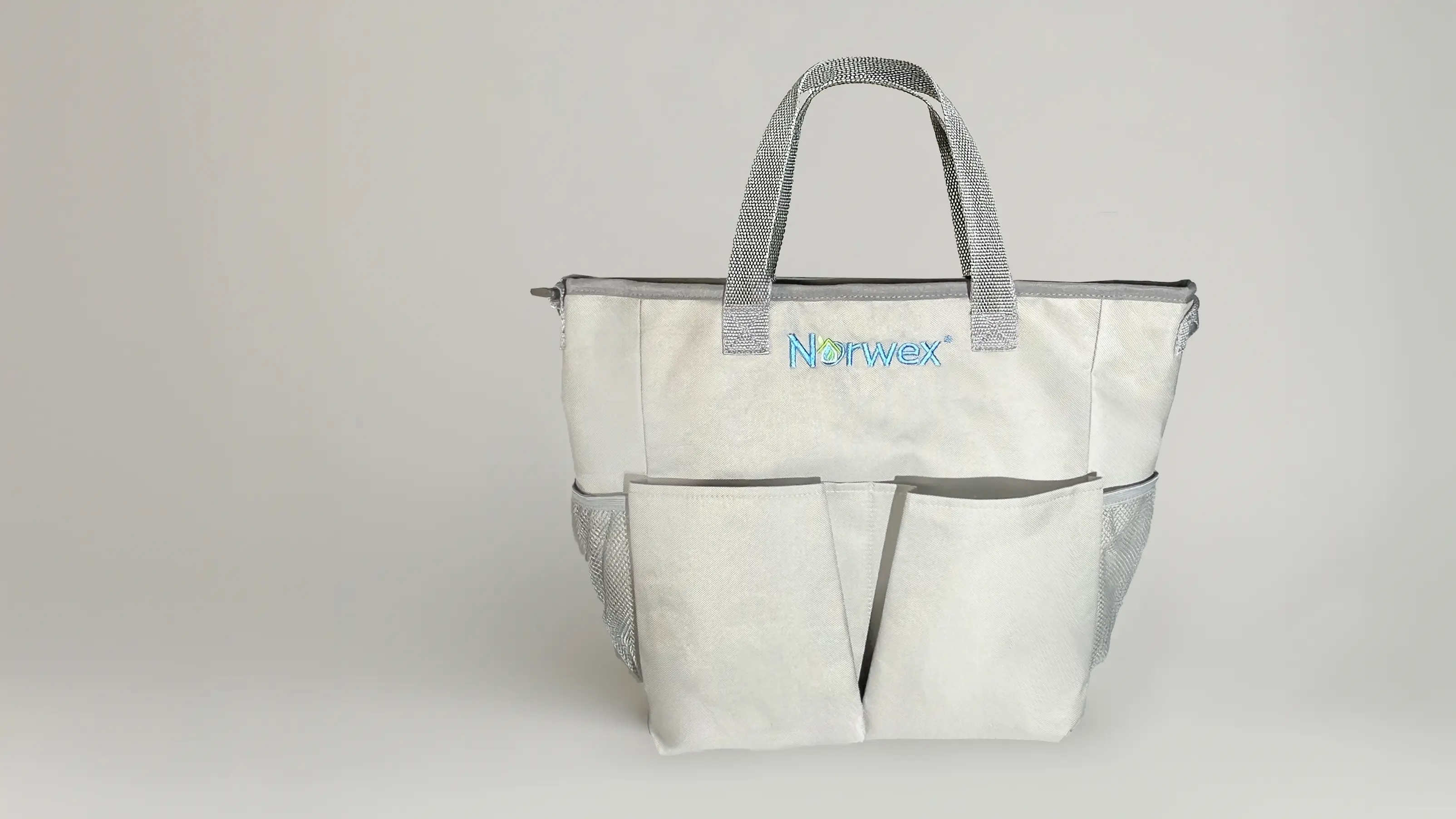 light gray Norwex tote bag with mesh side pockets and sturdy handles, featuring the Norwex logo