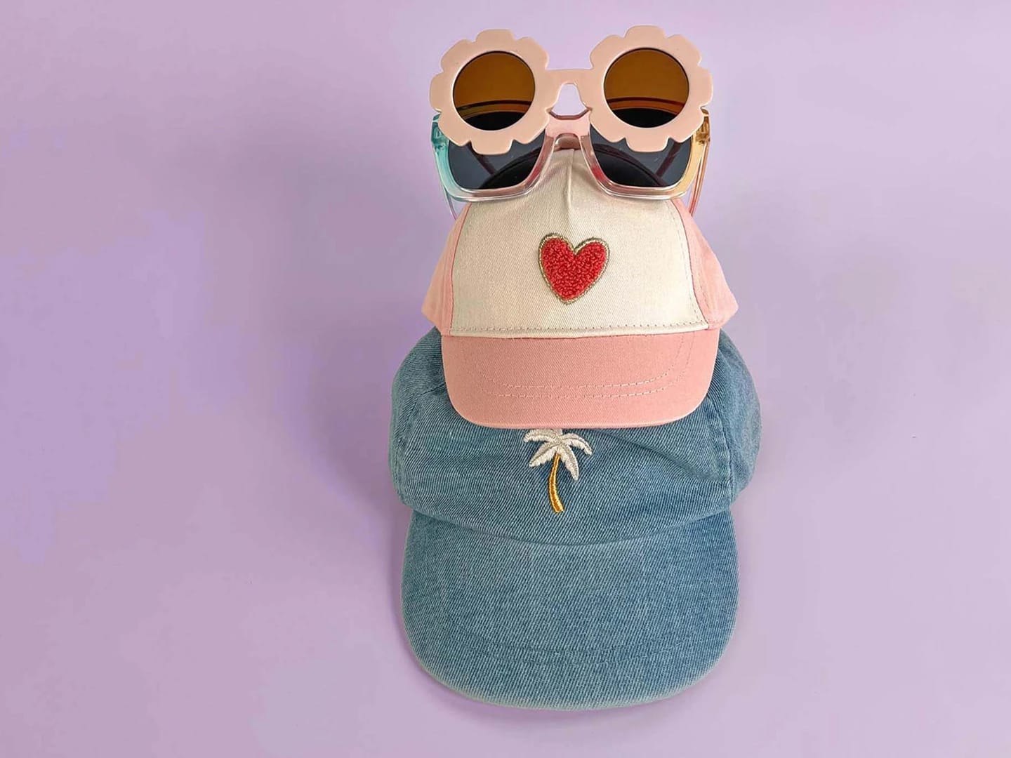 A playful arrangement of hats, including a cap with heart decorations, highlighting products from Orchestra