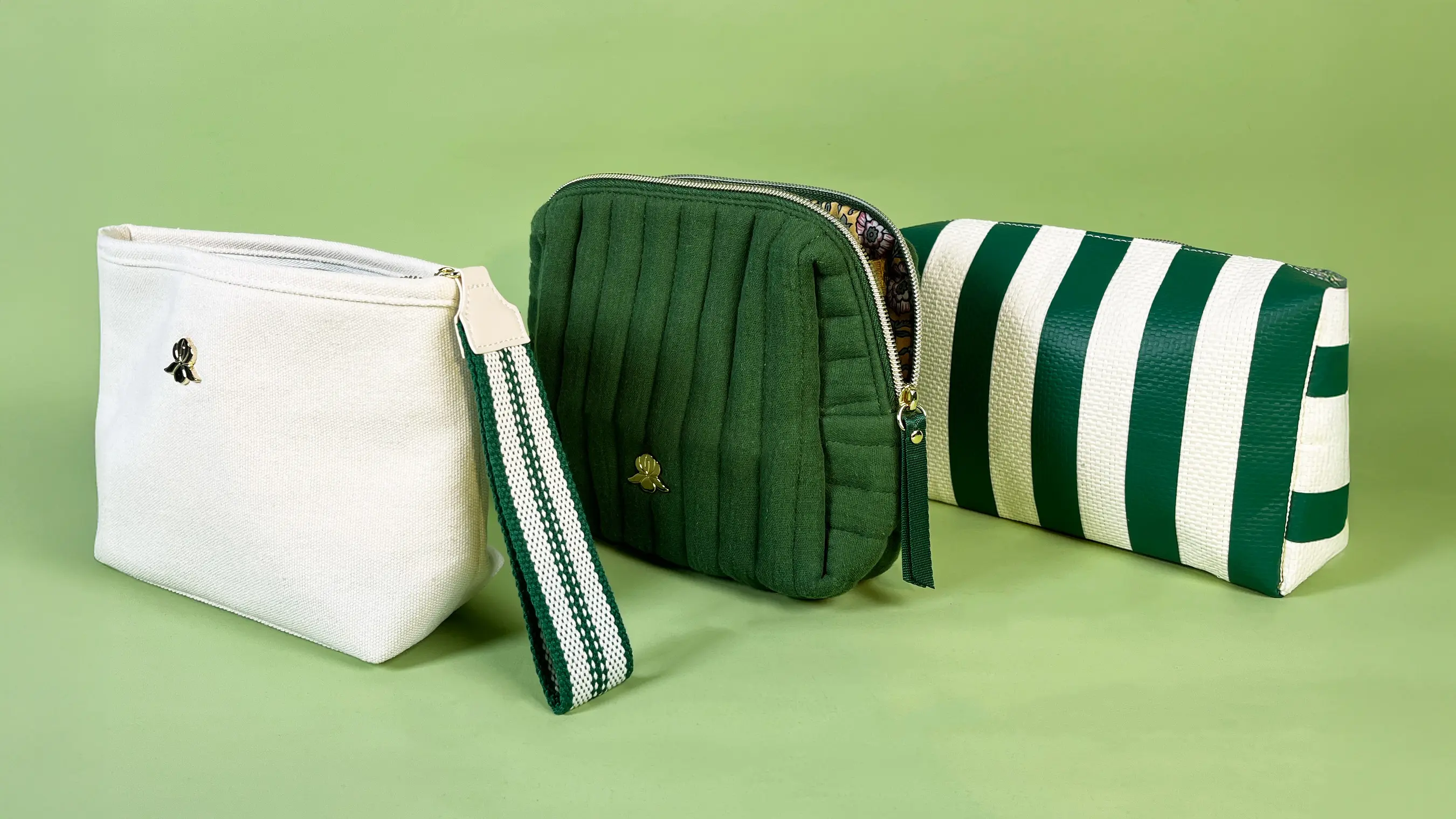 three green & white cosmetic bags in varied styles, representing Sisley's chic accessory collection.​
